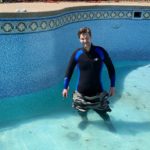 Man standing in shallowing unground swimming pool while wearing a wetsuit